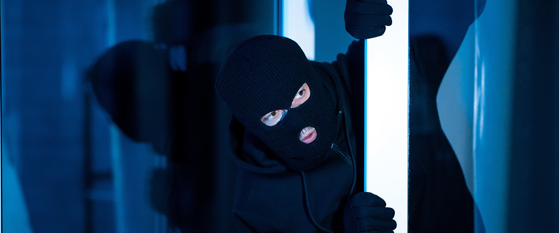 Imagem de um bandido todo de preto e rosto coberto por uma máscara preta.
