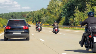Três motos ultrapssando um carro na estrada.